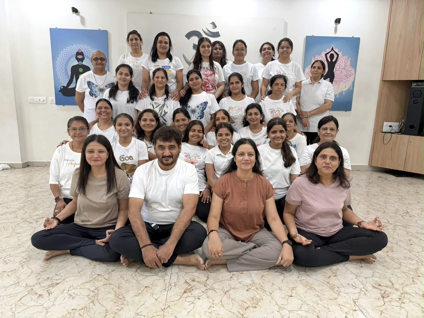 A large group of students seated and standing together inside Shraddha Yoga Space